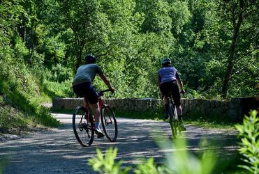 Due ciclisti su bici da corsa pedalano lungo una strada